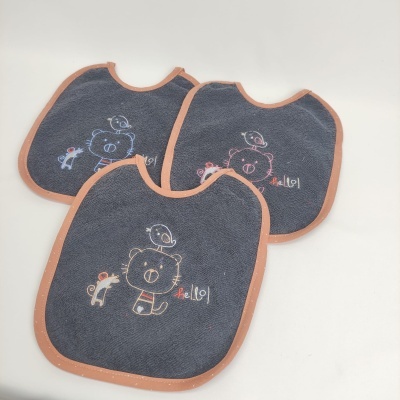 Três babetes de tecido cinzento escuro com bordados coloridos e acabamento rosa claro