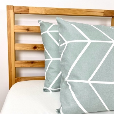 Almofadas cinza-azul com padrão branco numa cama de madeira clara