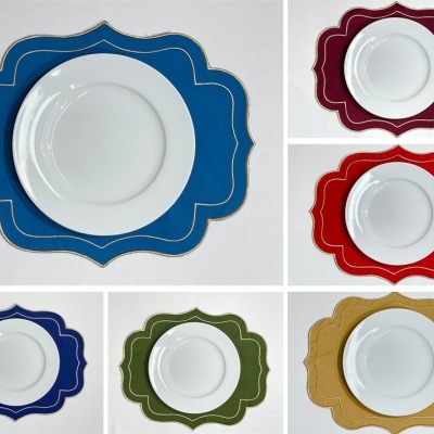 Pratos brancos sobre bases decorativas coloridas com bordas douradas.