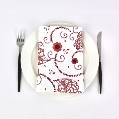 prato branco com guardanapo branco de padrão floral vermelho, garfo e faca à esquerda e direita