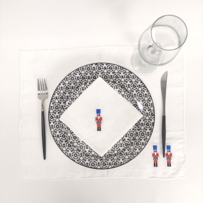 Mesa posta com prato decorado, guardanapo, talheres, copo e três soldados decorativos