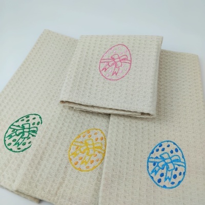 Quatro panos de cozinha bege com bordados coloridos de ovos de Páscoa