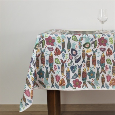 Toalha de mesa colorida com padrão de peixes e flores sobre mesa de madeira