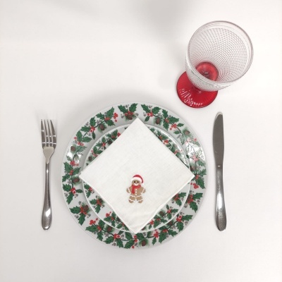 Conjunto de jantar festivo com prato de azevinho, guardanapo com boneco de gengibre, talheres e copo com base vermelha