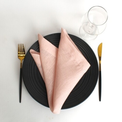 Conjunto de mesa com prato preto, guardanapo rosa, talheres dourados e pretos e copo de vidro