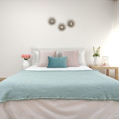 Cama com colcha azul clara e almofadas coloridas numa decoração de quarto minimalista