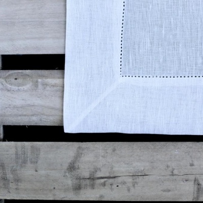 Guardanapo branco em tecido com bordado sobre madeira rústica