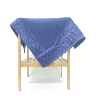 Toalha azul dobrada sobre suporte de madeira clara