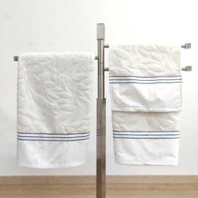 Toalhas de banho brancas com padrão texturizado e riscas azuis num suporte metálico