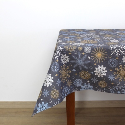Toalha de mesa cinza com flocos de neve azuis, brancos e dourados numa mesa de madeira