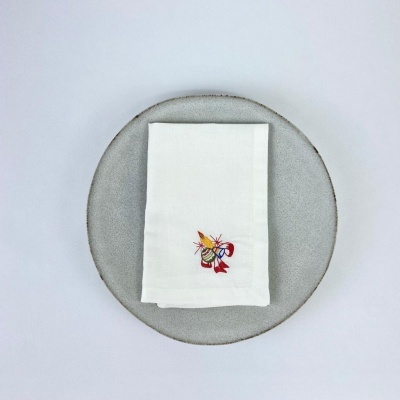 Guardanapo branco com bordado colorido numa prato cinzento