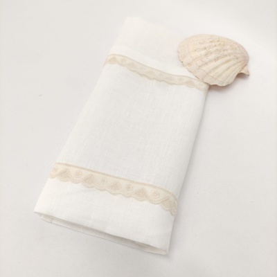 Guardanapo branco com bordas de renda bege e concha ao lado