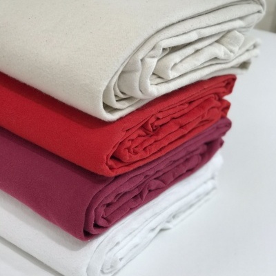 Quatro mantas dobradas em cores bege, vermelho, bordeaux e branco