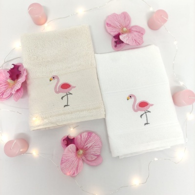 Toalhas bege e branca com flamingo bordado, flores e velas cor-de-rosa