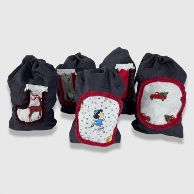 Cinco sacos de tecido cinza escuro com aplicações festivas coloridas