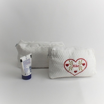 Duas bolsas de maquilhagem brancas com textura e bordado, e um tubo pequeno branco com tampa azul