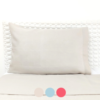 Travesseiro bege claro sobre cama com cabeceira branca texturizada