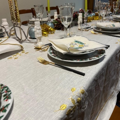 Mesa de jantar decorada com toalha branca bordada e pratos natalícios