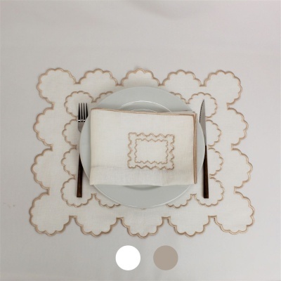 Jogo americano e guardanapo branco com bordadura castanha sobre prato branco e talheres