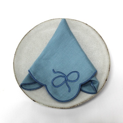 Guardanapo azul claro bordado sobre prato cerâmico cinza