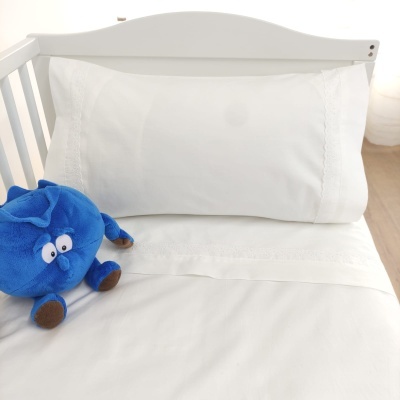 Cama de bebé com lençol branco e peluche azul