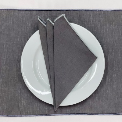 Prato branco com três guardanapos cinzentos e jogo americano cinzento escuro