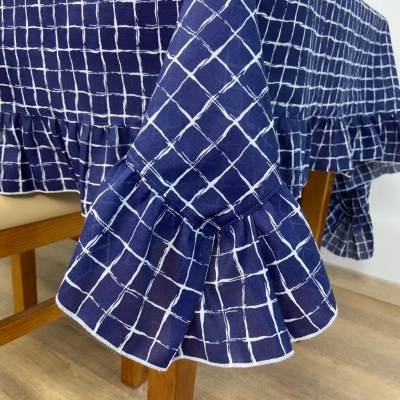 Toalha de mesa azul escura com padrão de quadrados brancos e guarda franzida sobre mesa de madeira clara