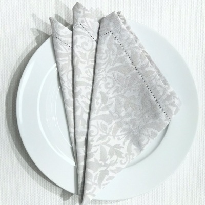 Guardanapo branco com padrão floral em placa branca