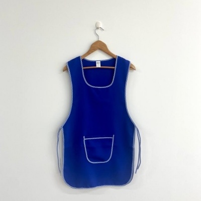 Avental azul com bordas brancas pendurado num cabide de madeira