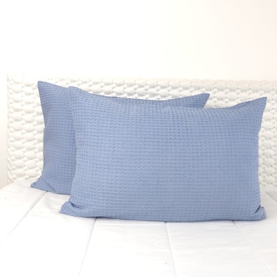 Duas almofadas azuis texturizadas sobre cama branca