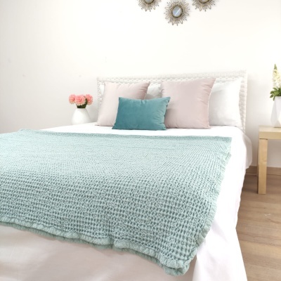 Cama com manta verde água e almofadas coloridas