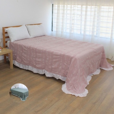 Cama com roupa de cama rosa e almofadas brancas junto a janela com cortinas brancas