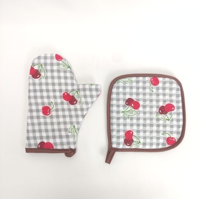 Luva térmica e pega-panela com padrão de grades cinzentas e cerejas vermelhas.