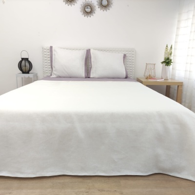 Cama com colcha branca e almofadas brancas com bordas lilás