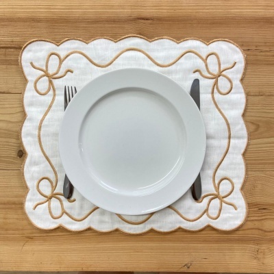 Prato branco, talheres e individual bordado em mesa de madeira