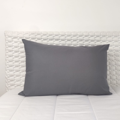 Almofada cinzenta em cama branca com cabeceira acolchoada