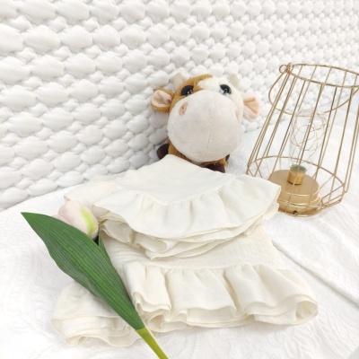 Conjunto de roupa branca para bebés com folhos, peluche de vaca e candeeiro dourado.