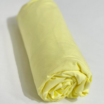 Têxtil amarelo claro dobrado em rolo sobre superfície branca