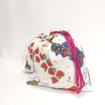 Sacos de tecido branco com padrão colorido e cordões em fundo branco