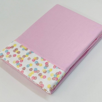 Lençol rosa com barra estampada de bolinhas coloridas dobrado