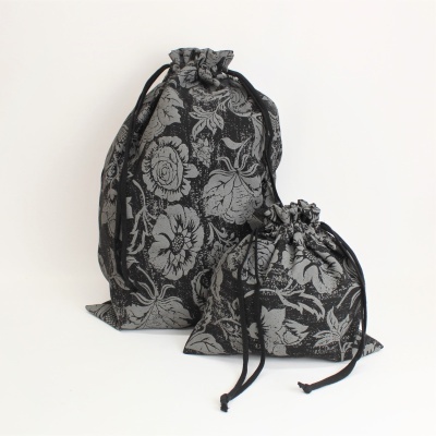 Duas bolsas de tecido com padrão floral cinza e preto com cordão de fecho