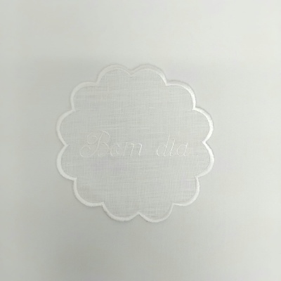 Toalha branca com bordado floral e texto 'Bom dia' em relevo