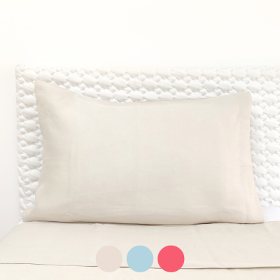 Travesseiro bege claro sobre cama com cabeceira branca acolchoada