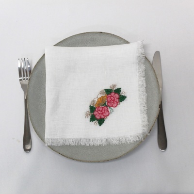 Jogo americano cinza com guardanapo branco bordado e talheres.