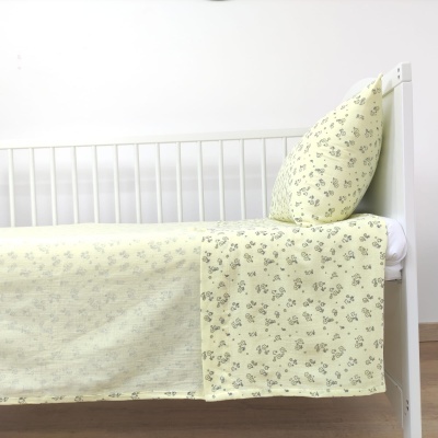 Cama branca com lençóis amarelos com padrão floral cinzento