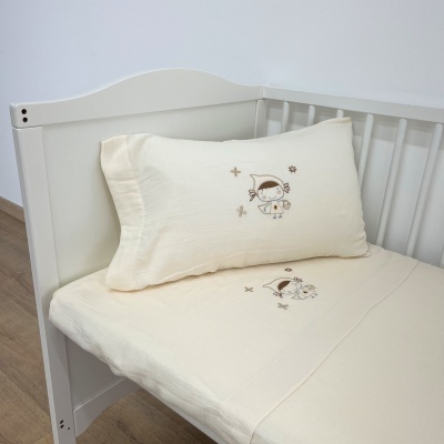 Berço branco com roupa de cama creme bordada com menina castanha