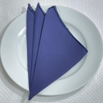 Guardanapo azul dobrado em prato branco sobre fundo branco texturizado