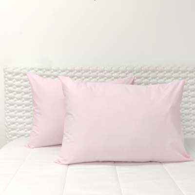 Duas almofadas cor-de-rosa claras num colchão branco com cabeceira acolchoada