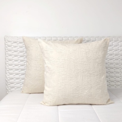 Dois almofadões bege claro com textura geométrica sobre base branca acolchoada