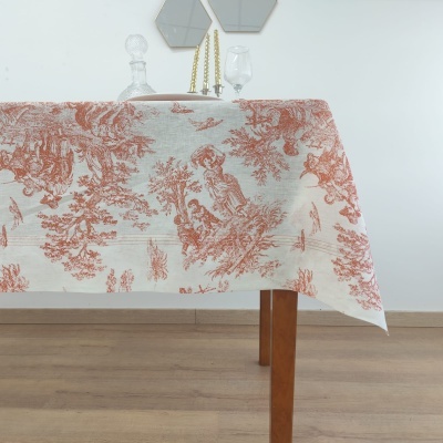 Toalha de mesa estampada em tecido claro com padrões em terracota pendurada numa mesa de madeira